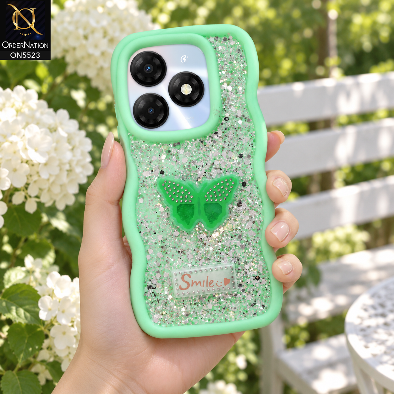 Itel P55 4G Cover - Sea Green - New Premium Smile Glitter Soft Case on the phone, held in a hand in a garden with hydrangeas (AI lifestyle render)