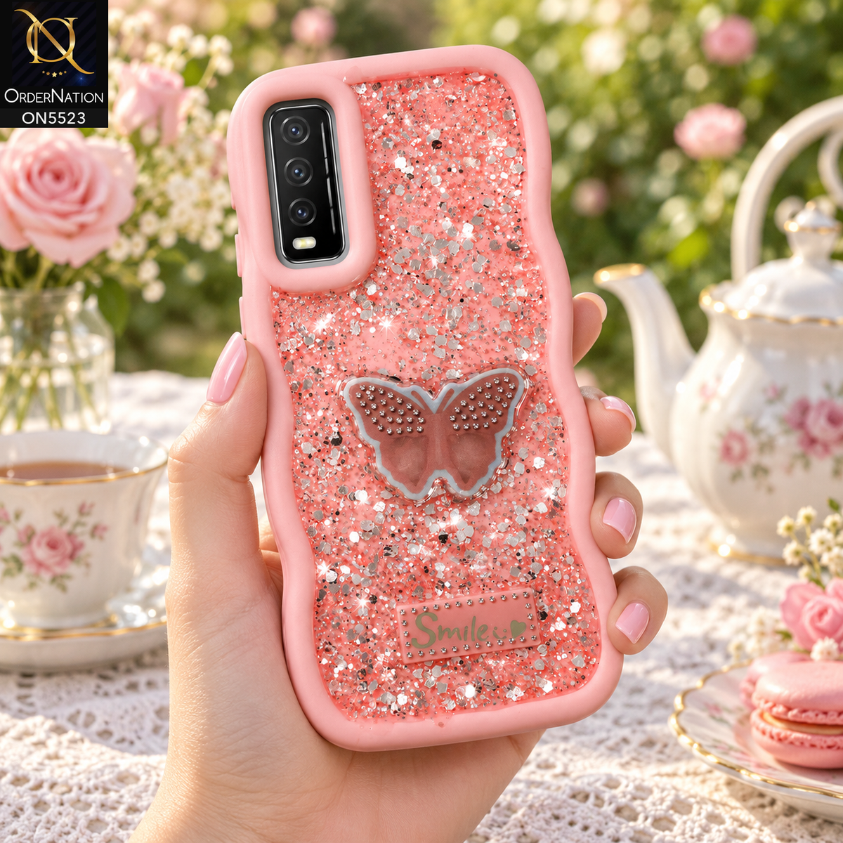 Vivo Y20 Cover - Pink - New Premium Smile Glitter Soft Case on the phone, held in a hand at a garden tea party (AI lifestyle render)