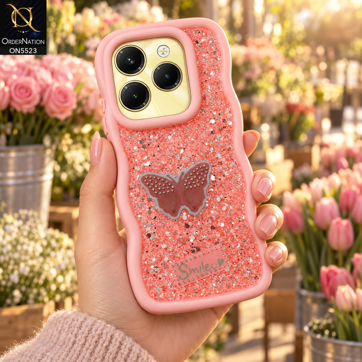 Infinix Hot 40 Pro Cover - Pink - New Premium Smile Glitter Soft Case on the phone, held in a hand at a flower market (AI lifestyle render)