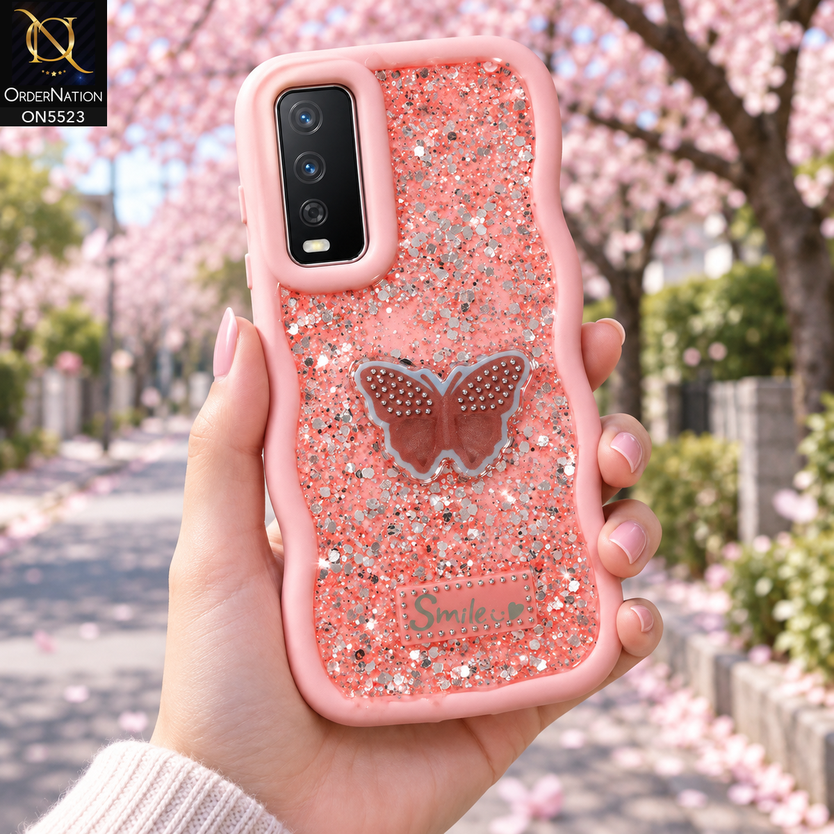 Vivo Y12a Cover - Pink - New Premium Smile Glitter Soft Case on the phone, held in a hand under cherry blossoms (AI lifestyle render)