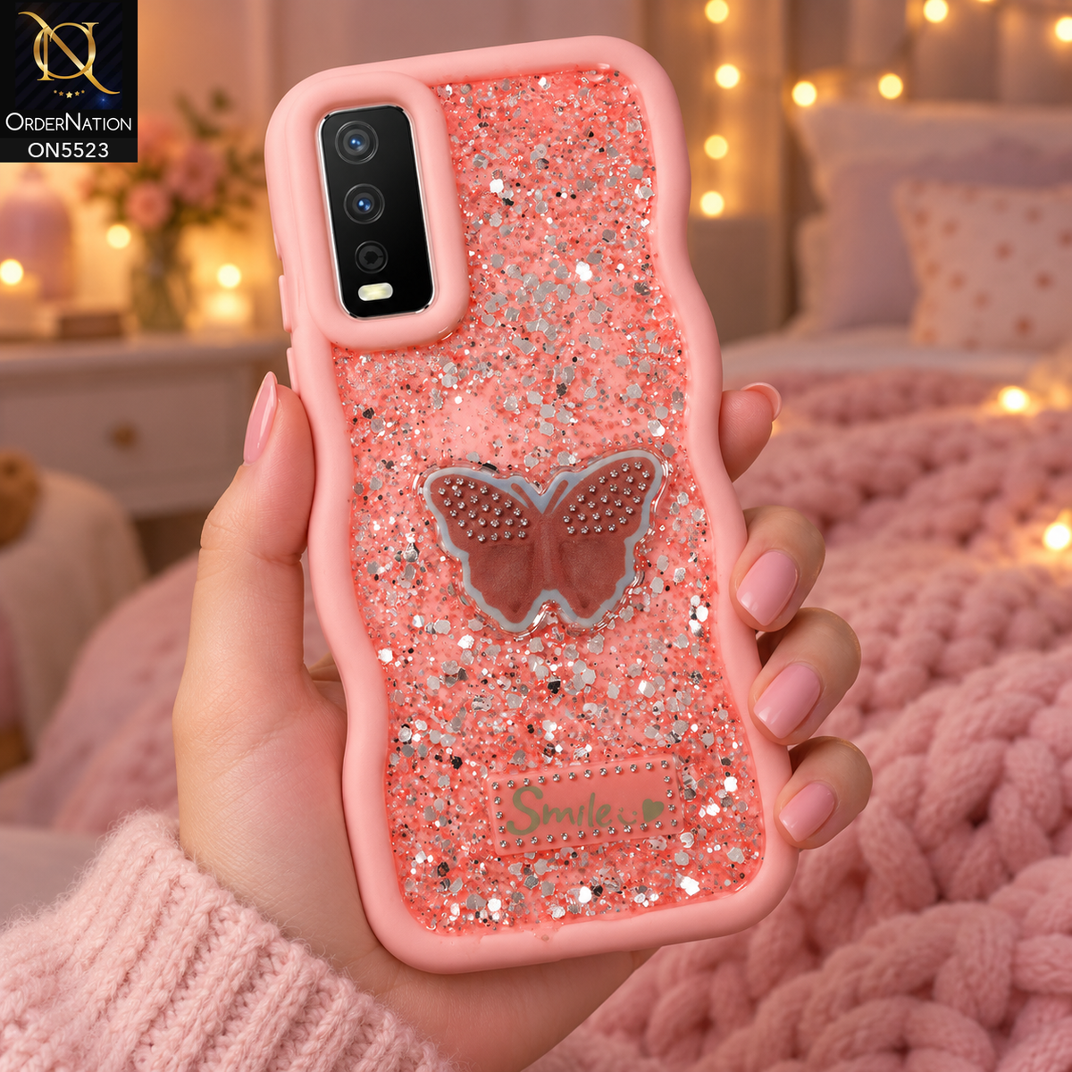 Vivo Y12s Cover - Pink - New Premium Smile Glitter Soft Case on the phone, held in a hand in a cosy bedroom with fairy lights (AI lifestyle render)