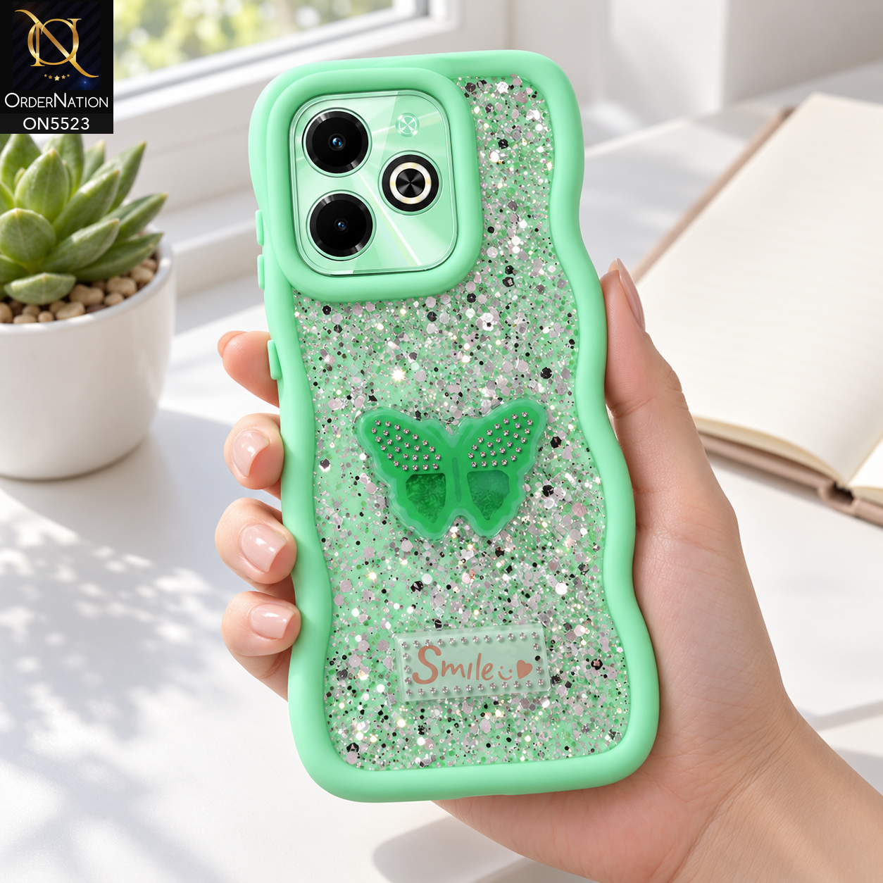 Infinix Hot 40i Cover - Sea Green - New Premium Smile Glitter Soft Case on the phone, held in a hand at a white desk (AI lifestyle render)