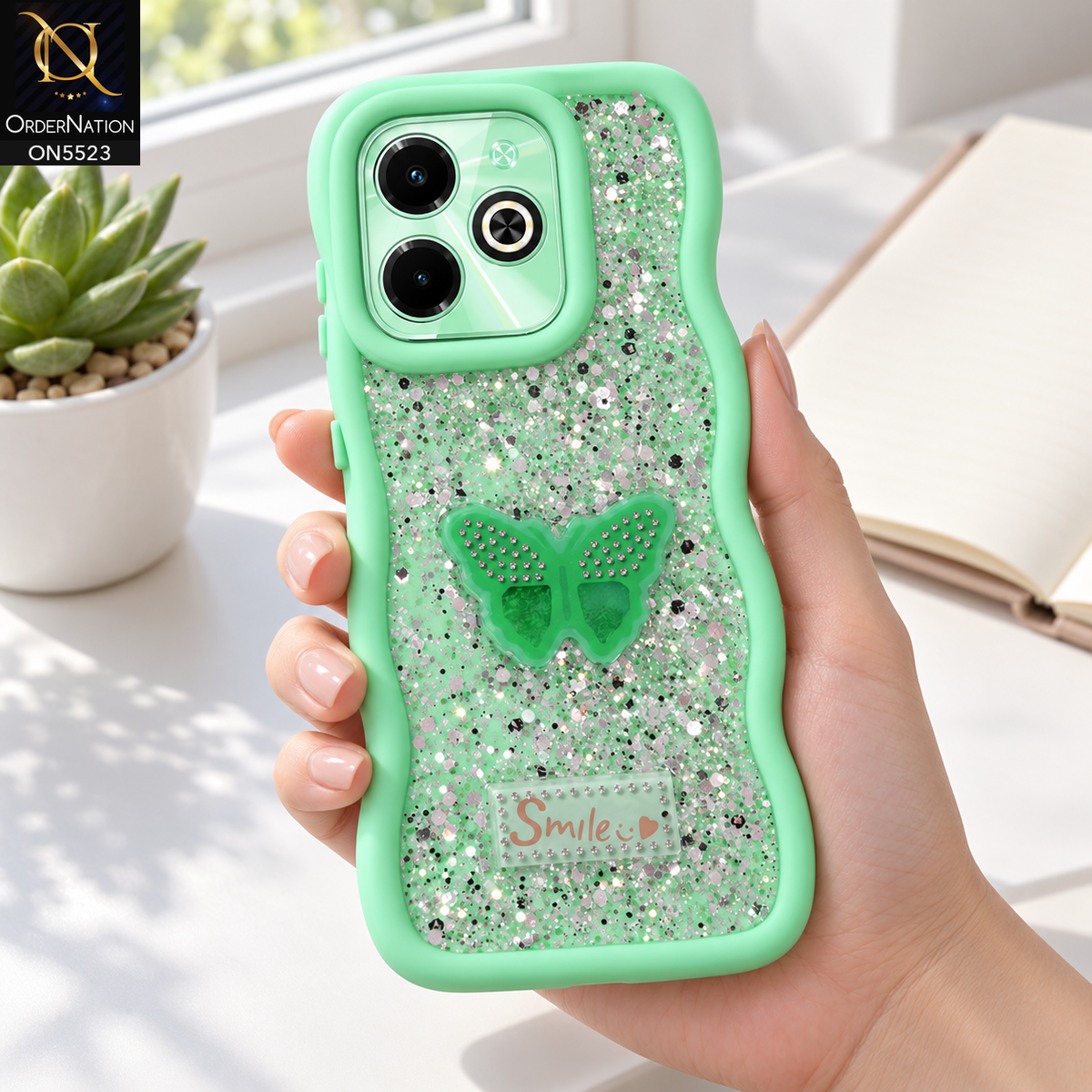 Infinix Hot 40i Cover - Sea Green - New Premium Smile Glitter Soft Case on the phone, held in a hand at a white desk (AI lifestyle render)