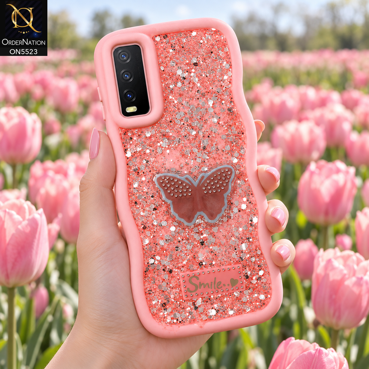 Vivo Y20a Cover - Pink - New Premium Smile Glitter Soft Case on the phone, held in a hand in a tulip field (AI lifestyle render)